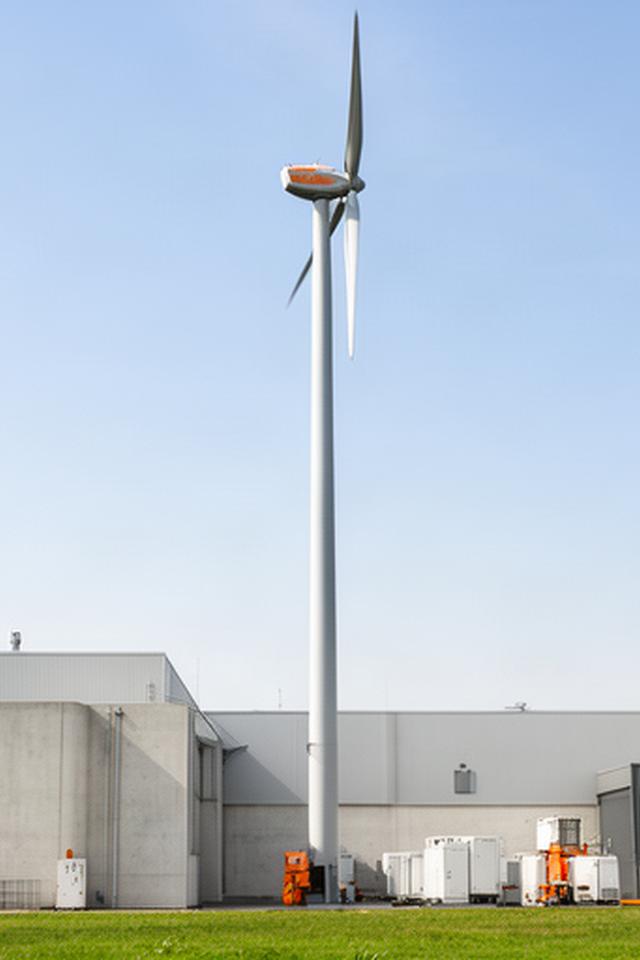 Aerogenerador E-44 junto a naves industriales para autoconsumo eléctrico en una zona abierta