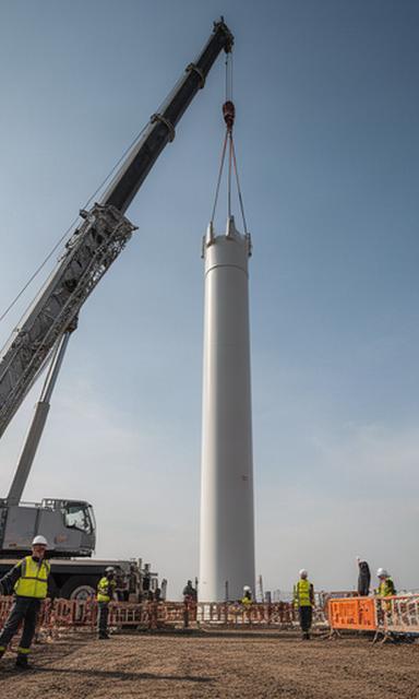 Grúa levantando una sección de torre eólica en una obra con medidas de seguridad